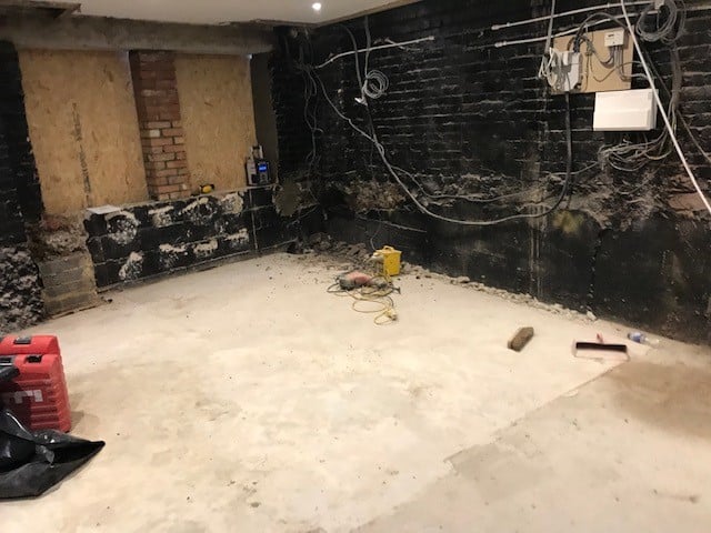 Empty right corner of ground floor flat basement with liquid membrane on wall