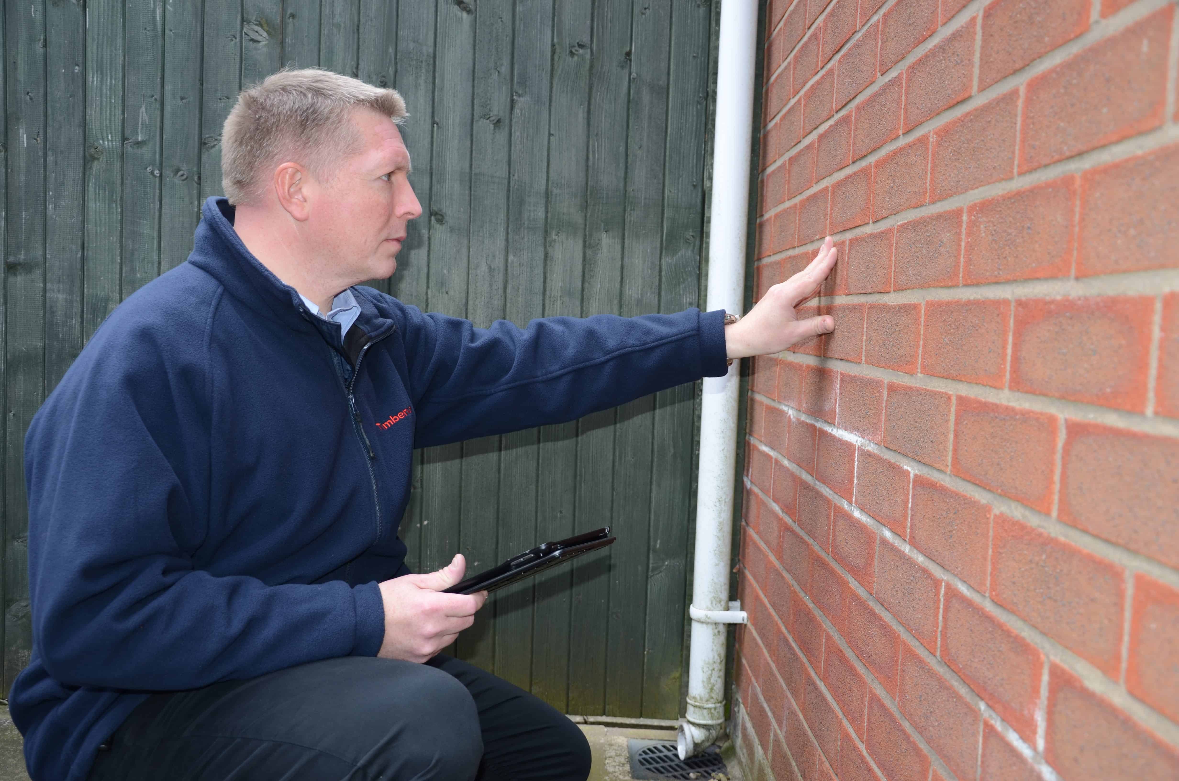 Man inspecting a wall for dampness