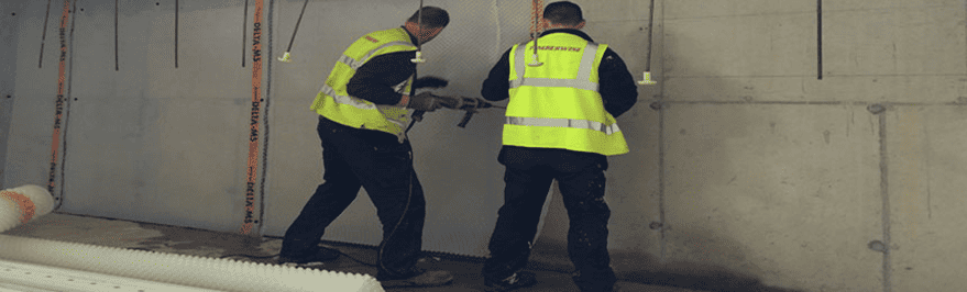 Engineers applying basement waterproofing to walls