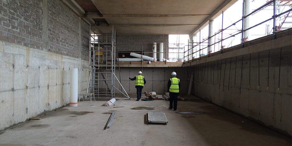 Timberwsie workmen in a basement preparing for damp proofing