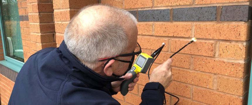 Surveyor carrying out external cavity wall survey