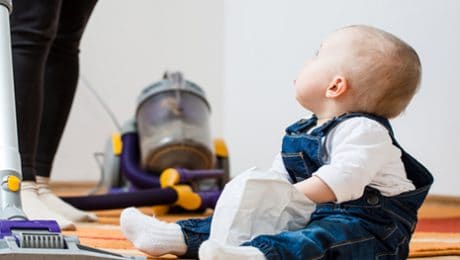 Child on floor with a vacuum cleaner