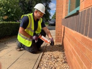 Engineer applying damp proof course to exterior wall