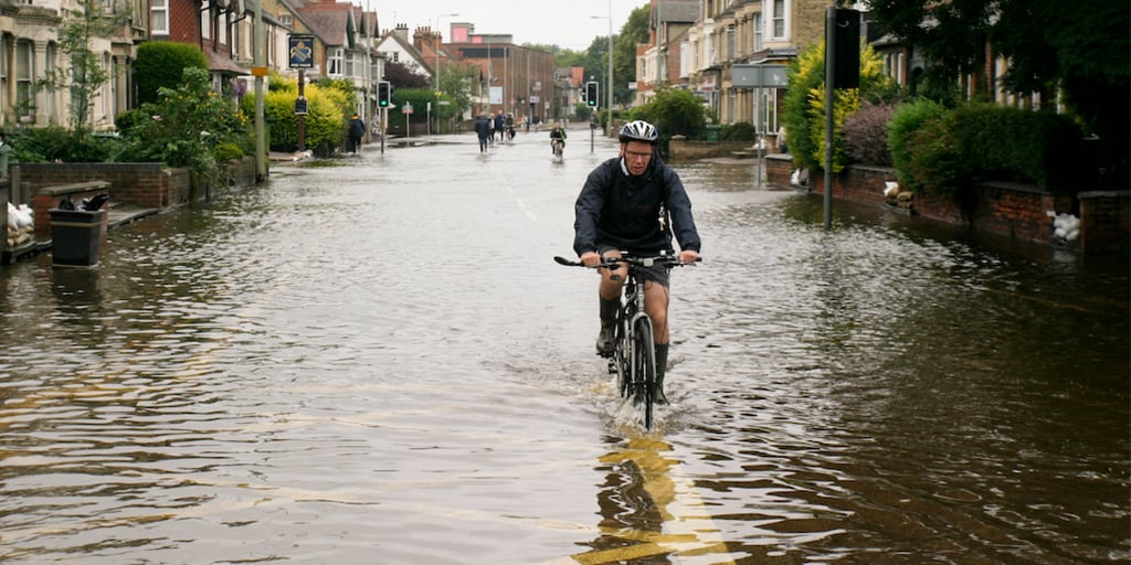 Cyclist cycling through flood water Cyclist cycling through flood water