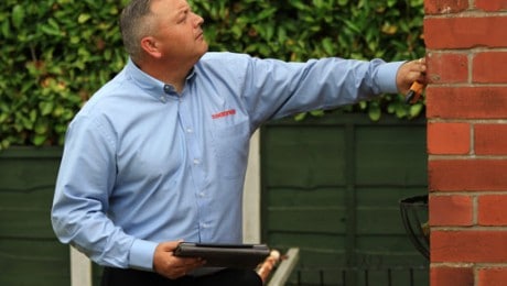 Surveyor inspecting outside wall of property