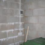 Closeup of basement wall with fuse box and electrical sockets before waterproofing solution installed