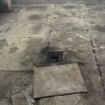 Closeup of basement floor with a broken tile