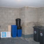 Basement room with bins and storage boxes before waterproofing solution installed