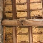 Closeup of timber ceiling beam with signs of woodworm
