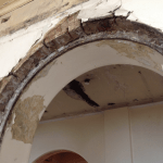 Flaking plaster and exposed brick on archway in St Michaels college