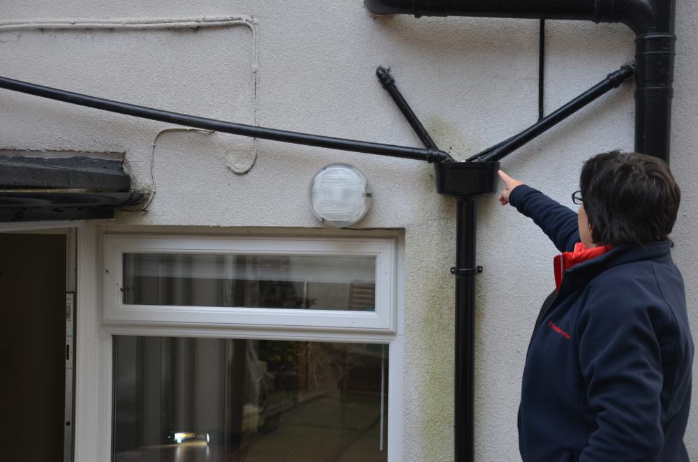 Female surveyor expecting the rainwater goods on a house