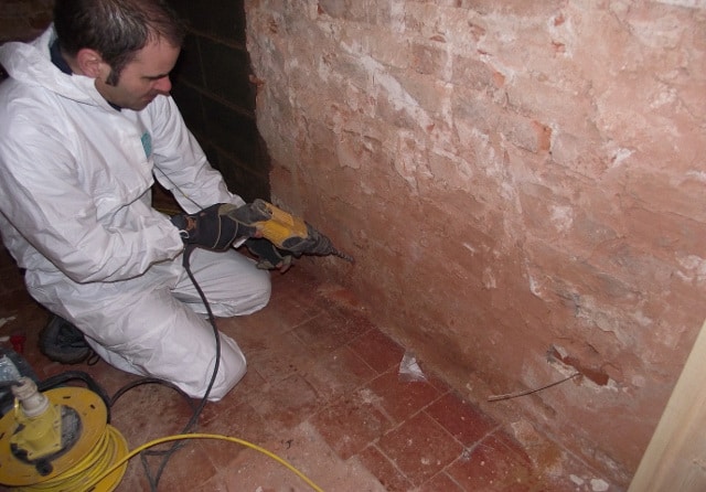 Technician inserting damp proof course into wall