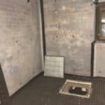 Exposed sump pump chamber surrounded by walls covered in waterproofing membrane in Liverpool basement