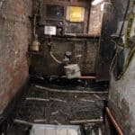 Basement corridor with black tarpaulin covering floor and manhole cover constructed