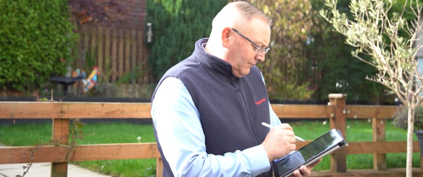 Surveyor drawing plans on tablet outside property