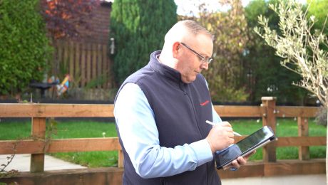 Male Timberwise surveyor stood outside a property with a tablet in hand