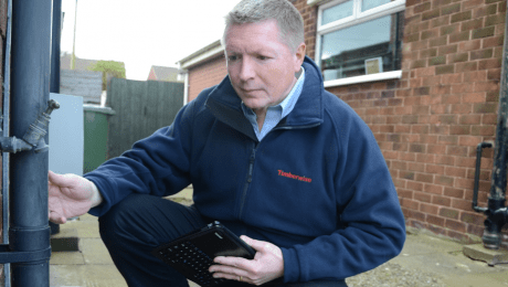 Man inspecting a drainpipe outside a house
