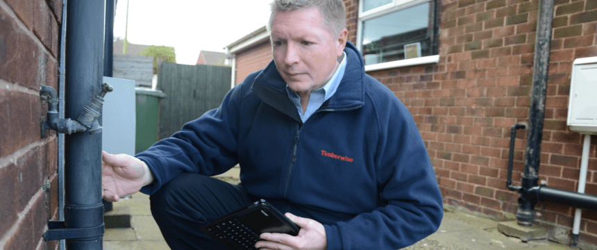 Man inspecting a drainpipe outside a house