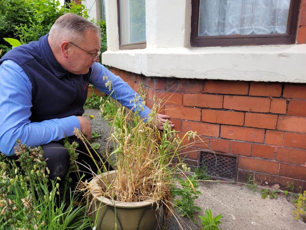 TImberwise surveyor knelt down outside a property carrying out external observations