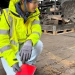 Surveyor in full PPE looking at wet rot affected wooden floor
