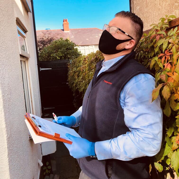 Surveyor stood with checkboard looking for external defects on house exterior