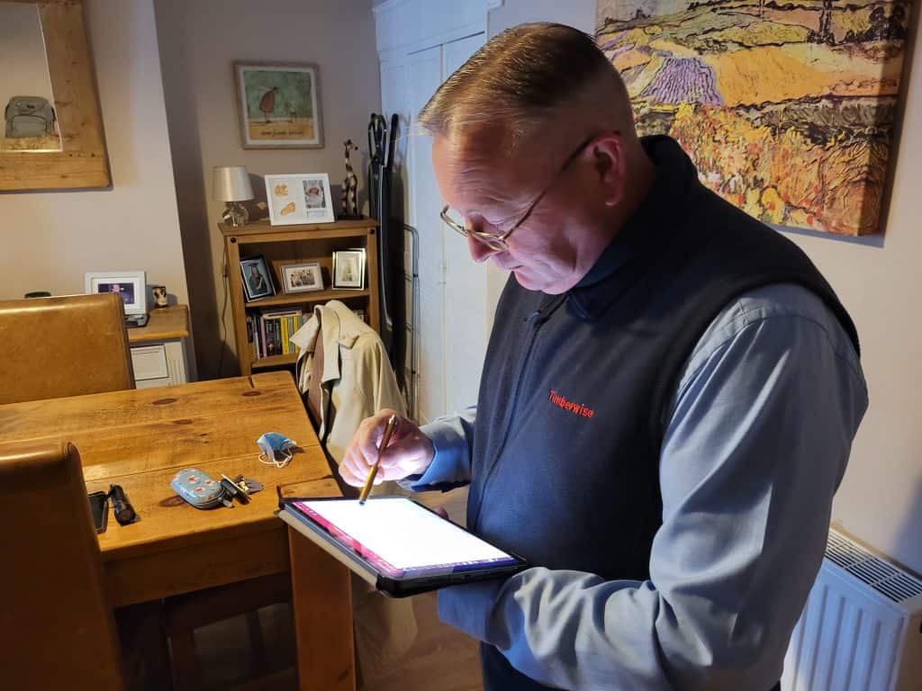 Surveyor drawing plans on tablet inside a property