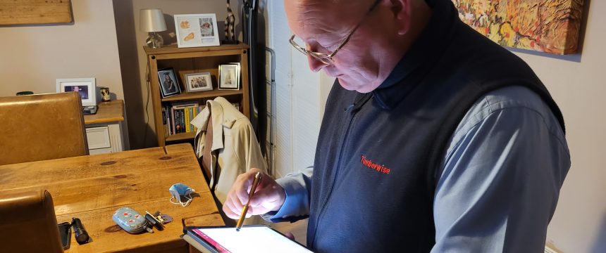 Surveyor drawing plans on tablet inside a property