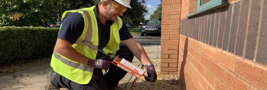 Technician carrying out damp proofing course to exterior wall