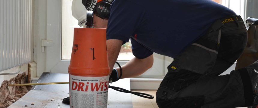 Technician applying damp proof injection cream to interior wall in house
