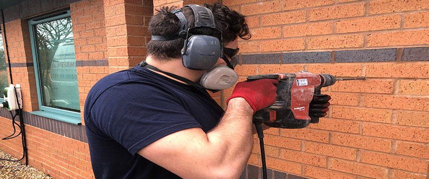 Technician drilling into wall and carrying out cavity wall tie replacement