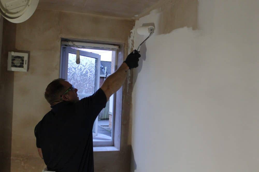 ThermalTek being painted onto wall Man inspecting a wall for dampness