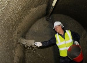 Man applying slurry to a basement wall from a bucket