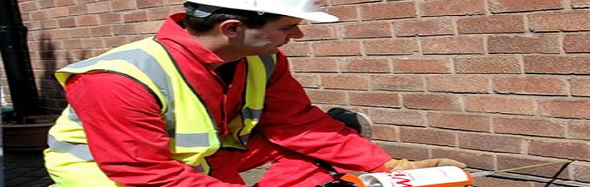 Closeup of engineer injecting damp proofing course into wall