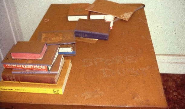 A chest of draws with a collection of books on top covered in dry rot spore dust