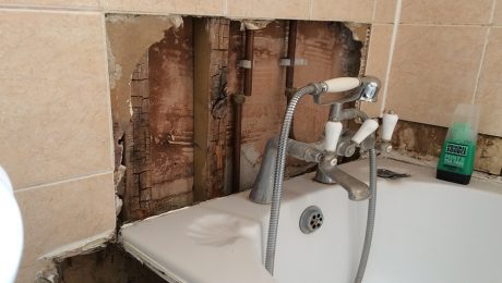 Exposed wet rot decaying timbers behind a bath tub in a bathroom